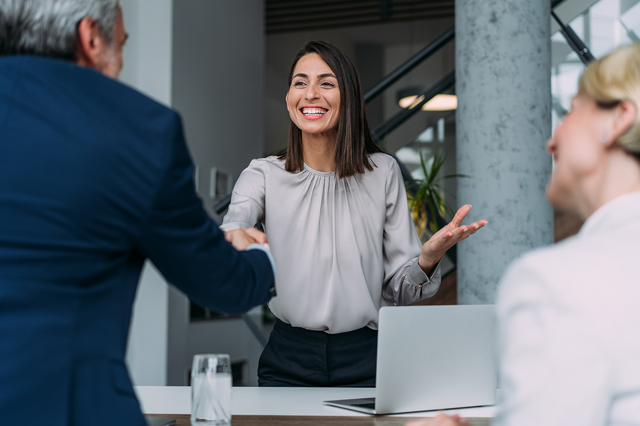 Two business professionals shaking hands in a modern office setting